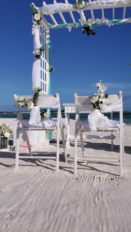 beautiful white chairs decorated with wedding bouquets of white roses, caribbean beach