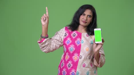 mature beautiful indian woman showing phone and pointing up