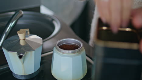 woman hands pouring coffee in moka pot preparing beverage for brewing close up.