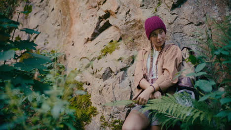 smiling woman day dreaming while leaning on rock in forest