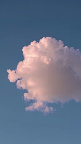 a serene video captures a fluffy cloud against a clear blue sky, shot from a low angle