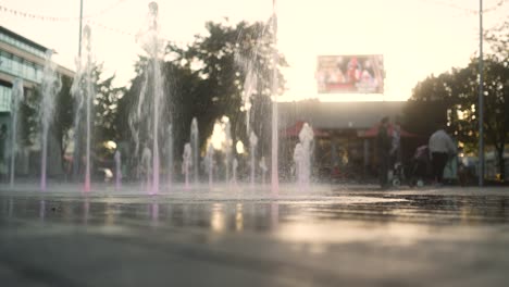 fountains in dundalk city center in front of a setting sun, as a family play by the water