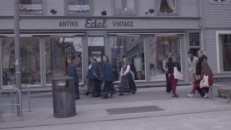female high school students in traditional clothing walk on the concourse in tromso, norway during norwegian constitution day. tracking shot