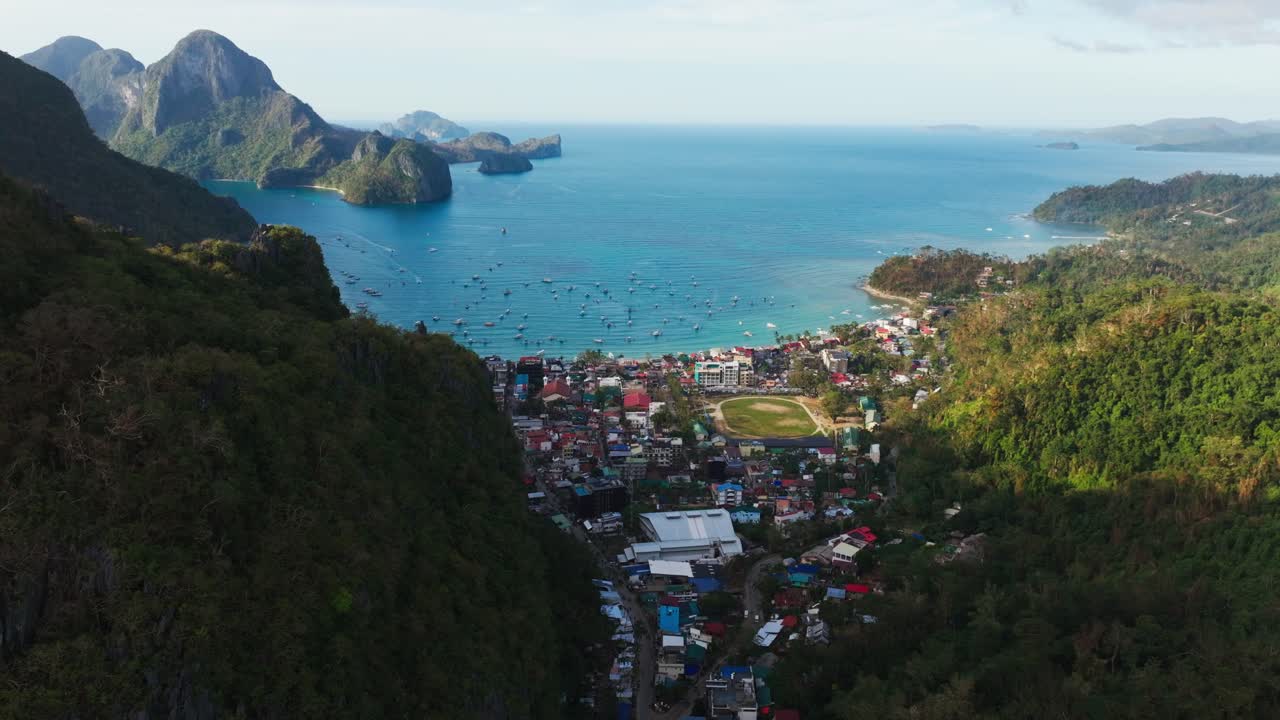 Bredt luftfoto viser El Nido by, bugtbåde, bakker i dagslys, Filippinerne