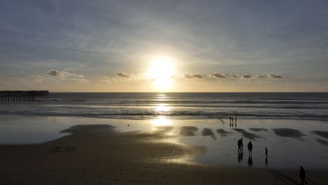 drone shot flying over beach into setting sun