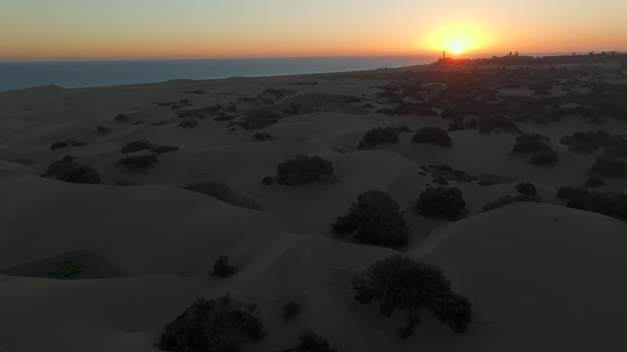 Lot nad wydmami plaży Maspalomas podczas zachodu słońca i z latarnią morską Maspalomas w tle