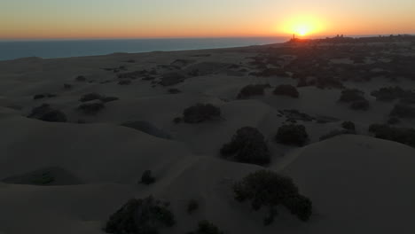 Flug-über-Die-Dünen-Des-Strandes-Von-Maspalomas-Während-Des-Sonnenuntergangs-Und-Mit-Dem-Leuchtturm-Von-Maspalomas-Als-Hintergrund