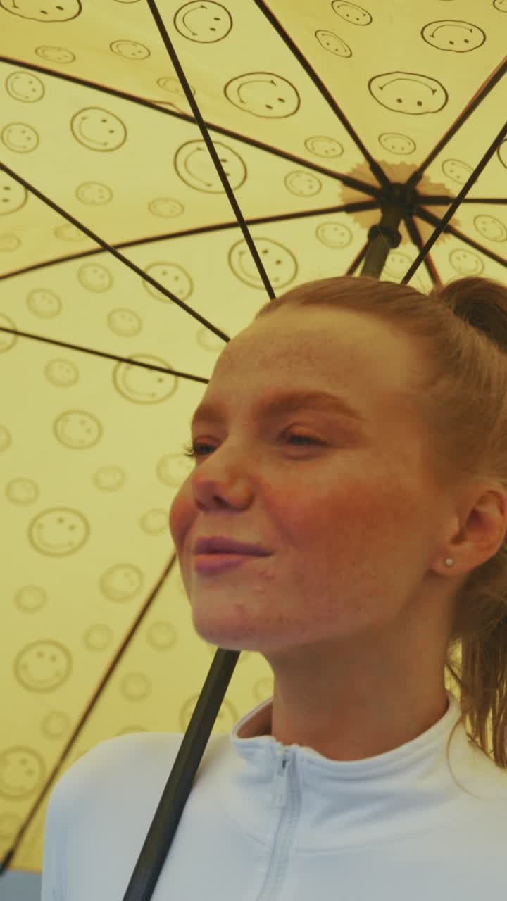 Captivating Close-Up Portrait of a Young Woman Under a Cheerful Yellow Umbrella with Smiley Faces, Capturing Natural Beauty and Expressions