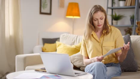 female teacher sitting on sofa having online class at home and showing charts and statistics