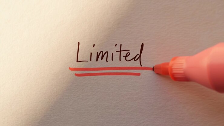 Fingertips guide a coral marker across off-white paper as parallel lines build beneath the handwritten word Limited, with soft warm illumination, visible paper grain, and centered framing.