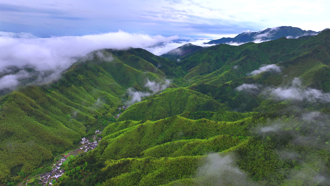 Aerial photography of high mountains shrouded in clouds and mist after rain, humid climate, and green forests shrouded in mist