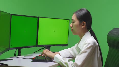 woman working on a computer with green screen monitors