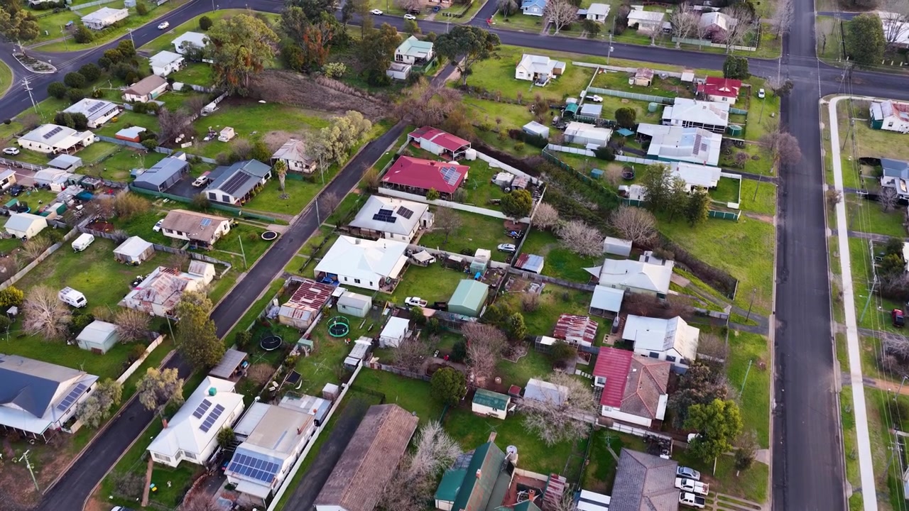 Ripresa aerea con drone dall'alto su tetti suburbani, giardini e strade di quartiere a Coonabarabran, Australia
