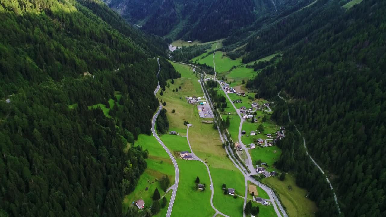 Wide tilt-up aerial exposes beautiful Austrian valley framed by towering peaks