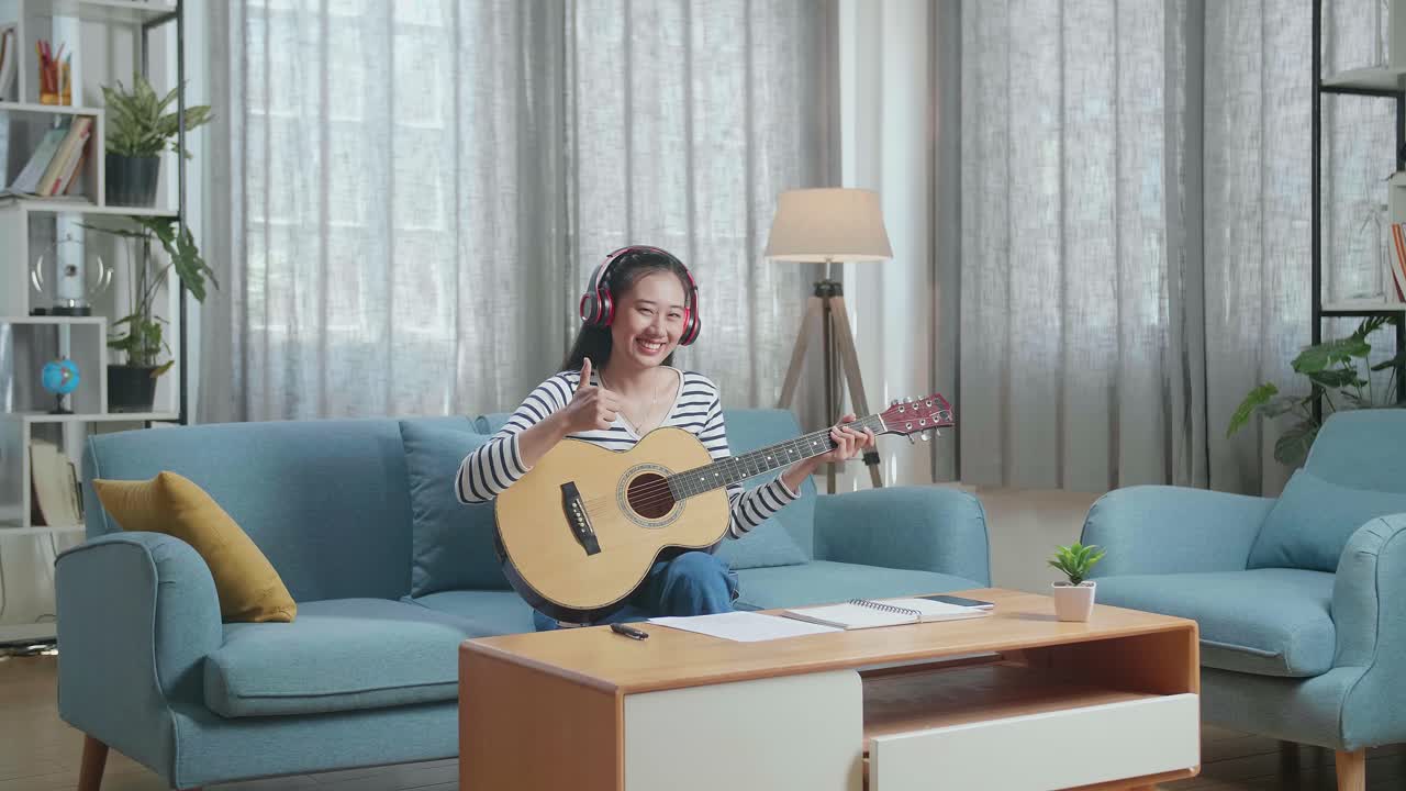 젊은 여성이 집에서 기타를 배우고 있습니다.