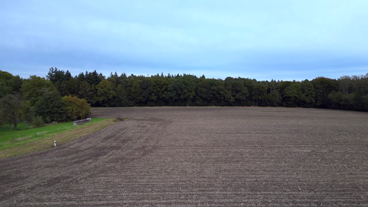 the edge of a forest bordering a plowed field in germany. Lovely aerial view flight fly reverse drone