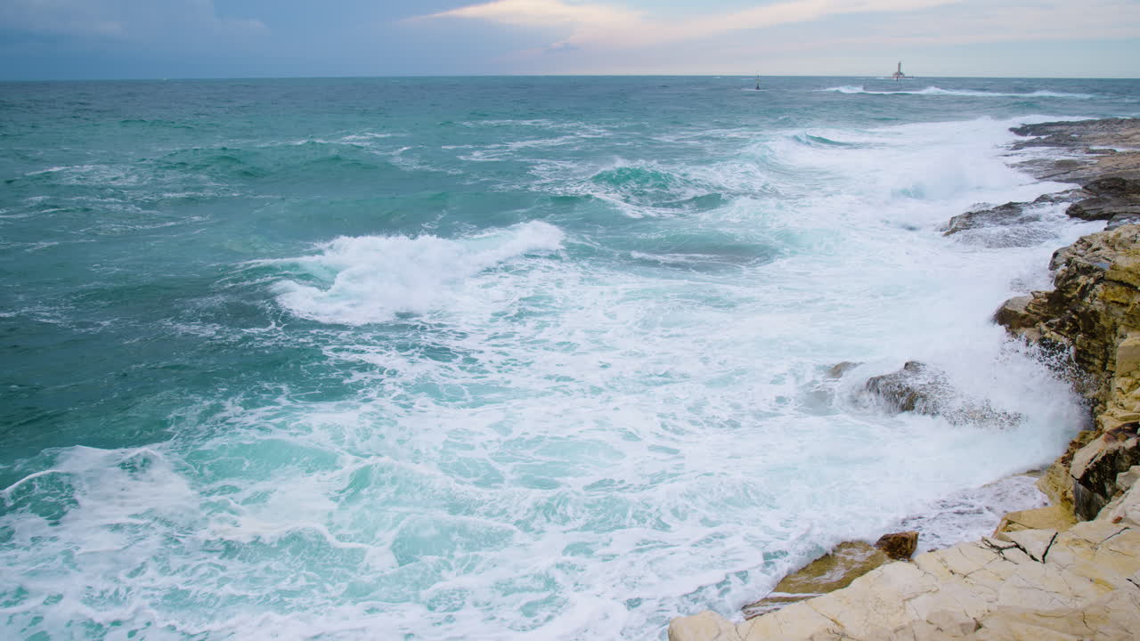 grandes olas del mar aplastando la costa rocosa, porer del faro y marca cardinal en el mar inquieto