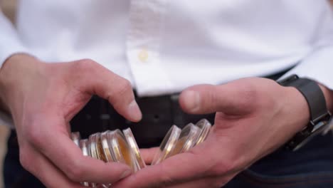 close up of businessman counting golden bitcoins in his hands