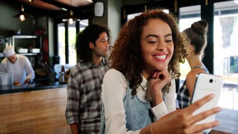 Mujer-Sonriente-Tomando-Un-Selfie-En-El-Teléfono-Móvil