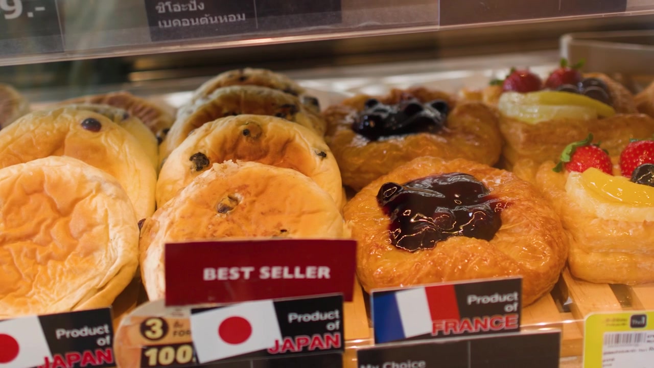 Un suave paneo de cámara a través de estantes llenos de cruasanes, pasteles daneses y panes de masa madre artesanales