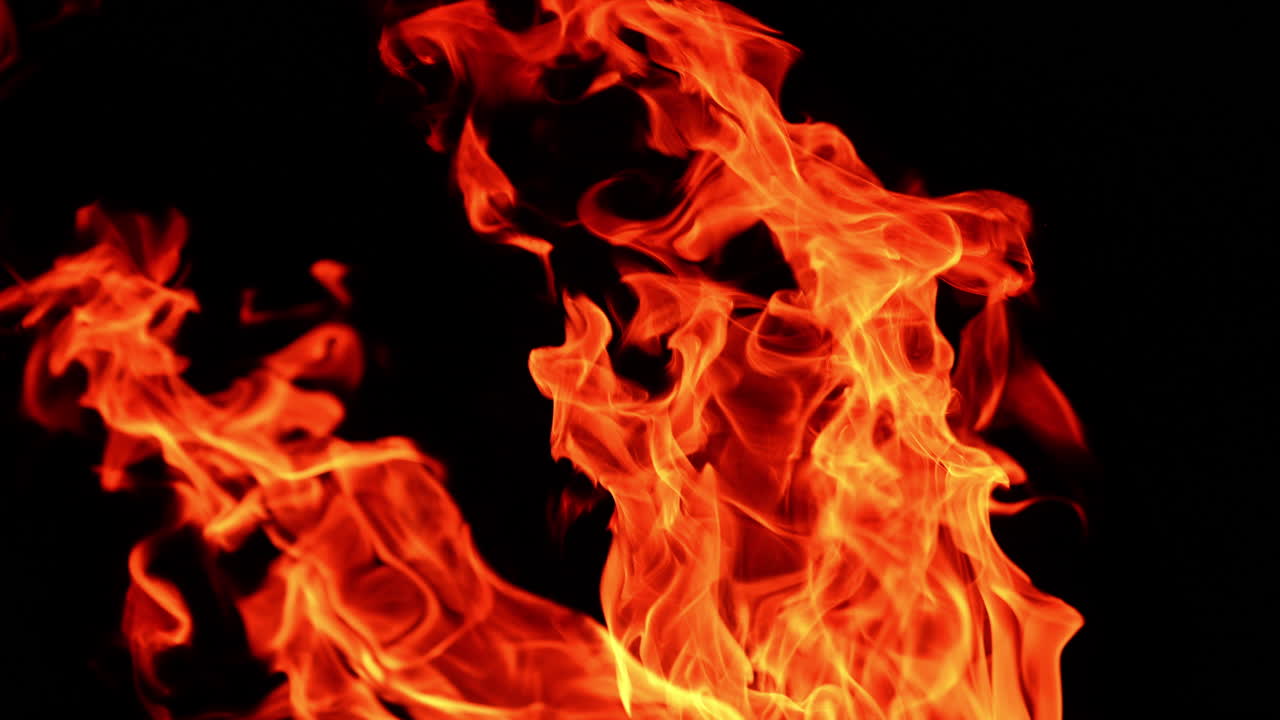 Red flame going up in the darkness. Isolated view of campfire burning at night. Close up.