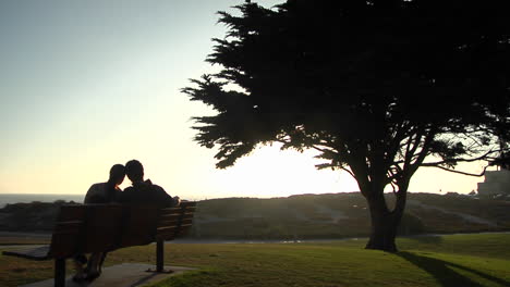 a couple snuggles on a park bench