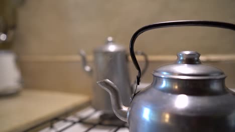 boiling kettle on cooker grill with steam exiting from spout