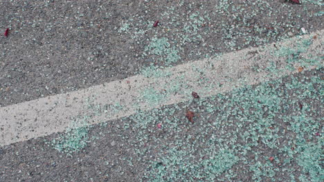 slow pan across broken car glass on the ground in a parking space