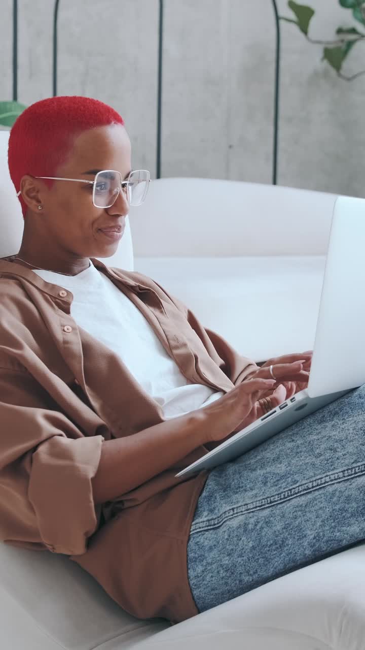 Young person with red hair works on laptop at home in the afternoon