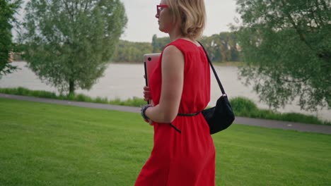 Beautiful-blonde-business-woman-with-a-laptop-walking-towards-the-bench-in-the-city-park