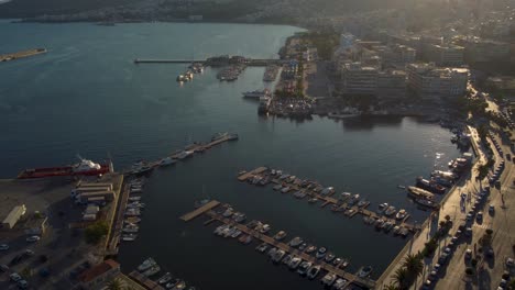 aerial of cityscape with busy road and boats docked on the port at sunset in greece