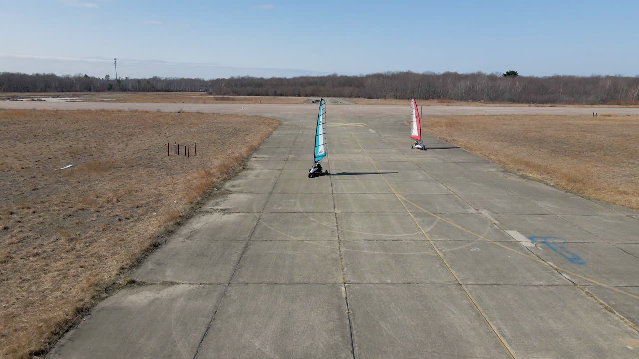 사용하지 않는 비행장에서 두 대의 직조 육상 항해용 버기를 추적하는 뒤로 이동하는 드론 영상