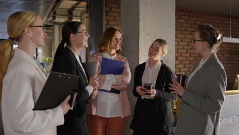 side view of a group of confident businesswomen in business clothes communicating during a short break in a modern office