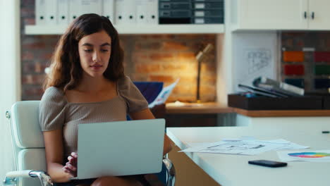 joven mujer de negocios sonriente trabajando en una computadora portátil en un escritorio en una oficina moderna