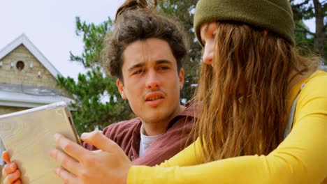 vista lateral de jóvenes skateboarders caucásicos geniales discutiendo en una tableta digital en un café al aire libre 4k