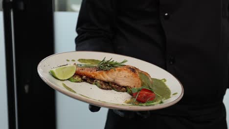 chef serving grilled salmon with vegetables