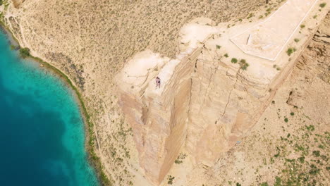 Man-Standing-On-Top-Of-Cliff-Overlooking-Blue-Lake-At-Band-e-Amir-National-Park-In-Bamyan,-Afghanistan