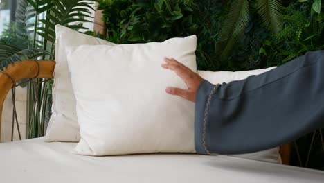 woman touching a pillow on a couch in a garden setting