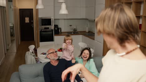 playful crazy young daddy performing parody to guess together with a family in living room interior