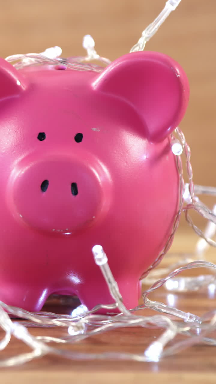 Piggy bank with fairy lights on wooden table