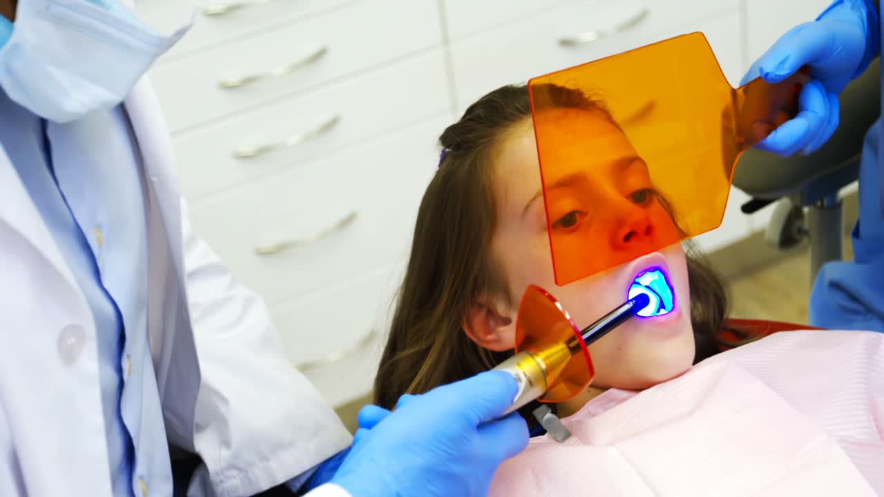 치과의사 들 이 도구 를 가지고 어린 환자 를 검사 하고 있다