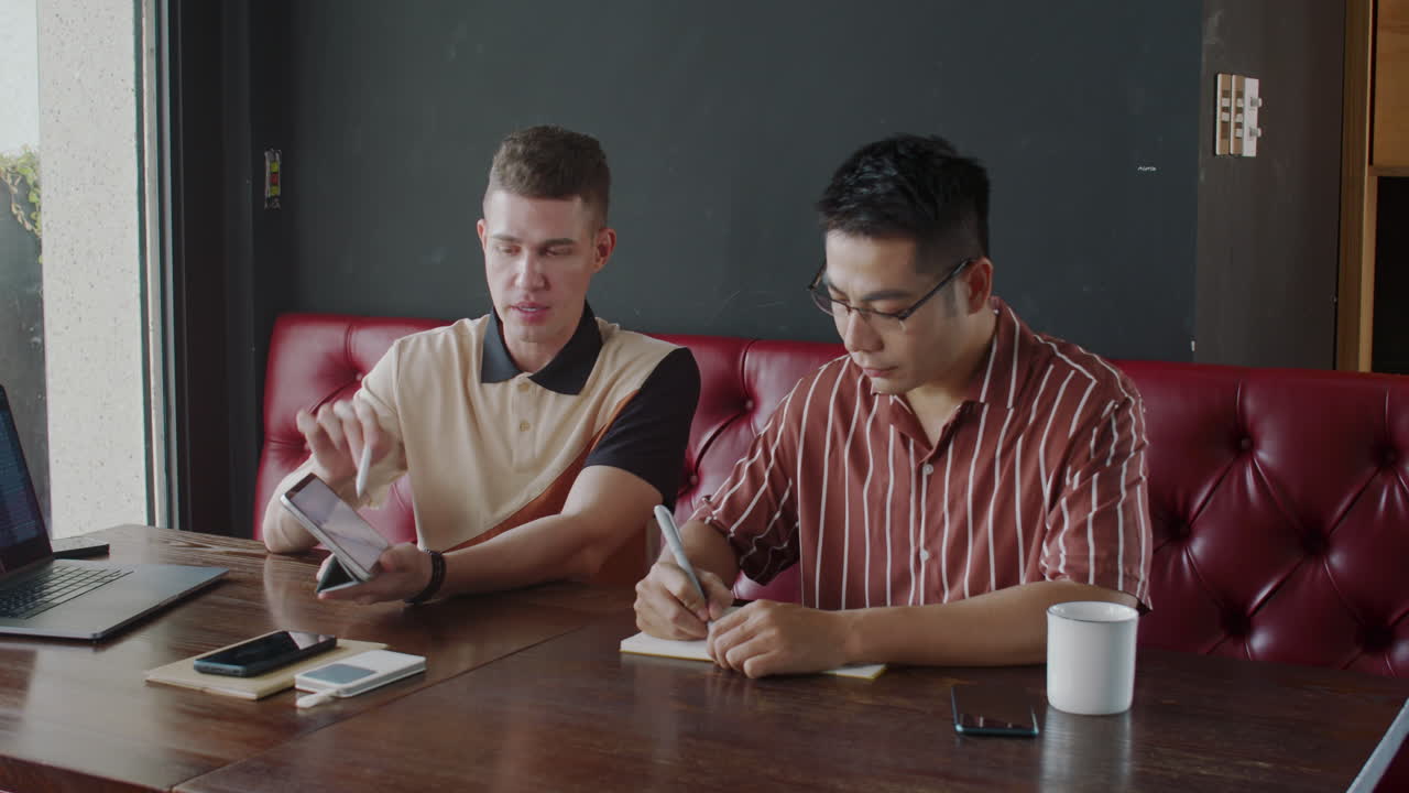 Analyst Giving Consultation to Businessman Pointing at Tablet with Chart in Cafe