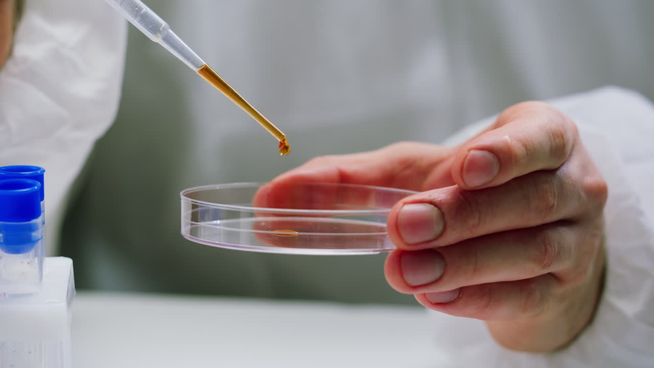 Scientist Dropping Liquid Sample into Petri Dish in Laboratory
