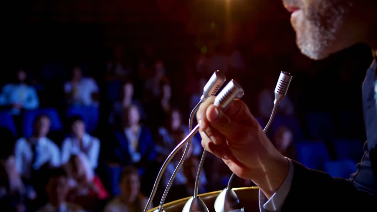 Imprenditore caucasico che parla sul palco a un seminario aziendale in auditorium 4K