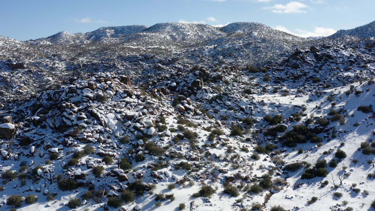 Paisaje invernal de colinas de granito en el Parque Nacional Joshua Tree cubiertas de nieve.