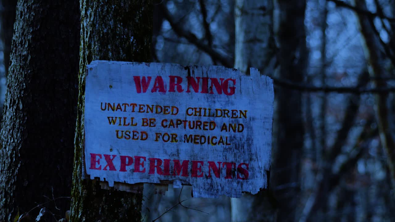 Dark eerie distressed sign warning of experimental medical procedures on children in remote woodland forest