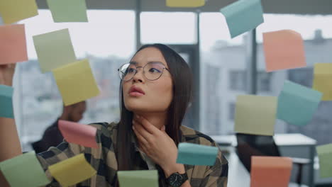 thoughtful freelancer pondering sticker wall office closeup. woman writing tasks