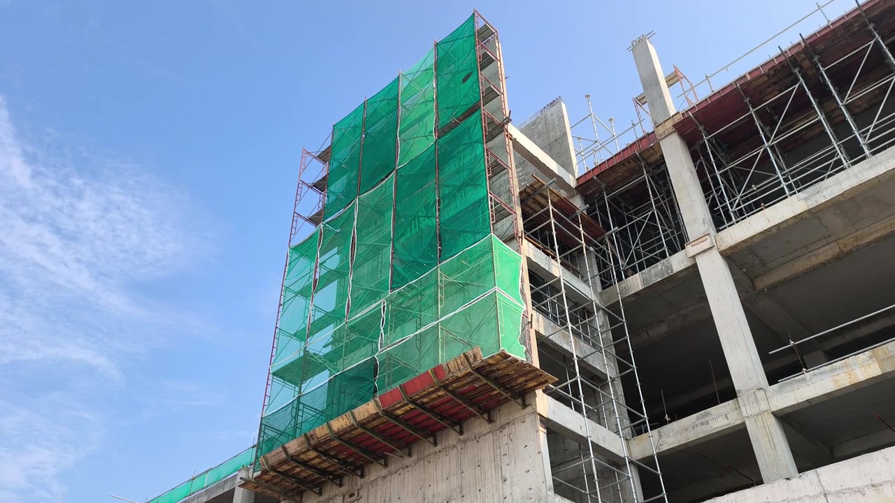 Una plataforma de trabajo en voladizo sostenida por soportes de andamio en un edificio. Contiene andamios adicionales utilizados para la construcción de muros exteriores.