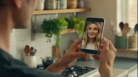 man on video call with woman while cooking in kitchen