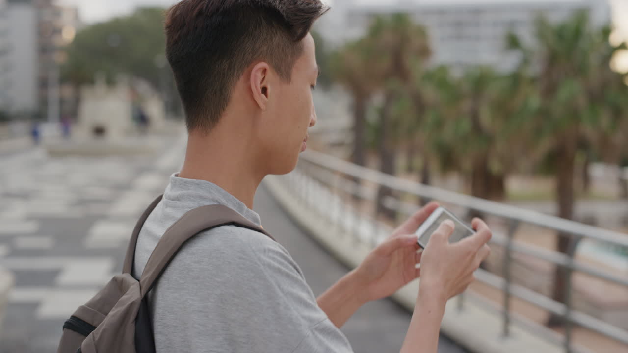 스마트폰을 사용하는 젊은 아시아 남성 관광객의 초상화 휴가 경험의 사진을 찍고 사진을 공유하는 것을 즐기는 미소 짓는 즐거운 휴대폰 카메라 기술